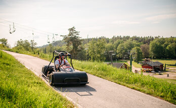 Bild på en av Flottbros Downhill bilar som susar ner för backen, gräset är grönt och solen skiner.