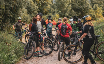 Bild på en grupp tjejer med cyklar och full utrustning som pausar i skogen